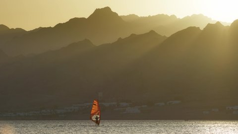 Panning shot of windsurfer on the background of sunset mountains. Dahab, Egypt