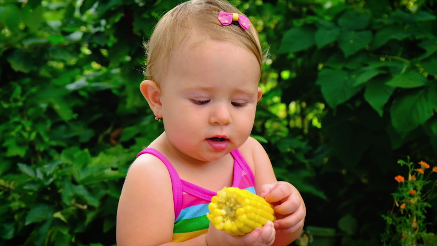 The child eats corn on the street. Selective focus.