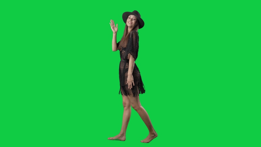 Side view of walking pretty summer woman greeting and sending kisses. Full body isolated on green screen background
