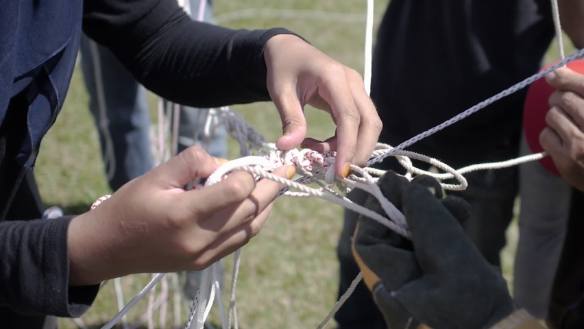 Human hands trying to untie tangled rope line, pulling on strings, many ropes with knots tie together. Tangled lines after kite fighting competition. Closeup slow motion Royalty-Free Stock Footage #1082025329