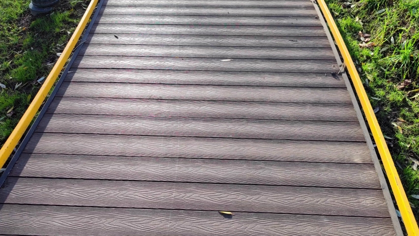 The texture of artificial gray wooden coating for walks and trips on a scooter and a bicycle piped. Path in the park for pedestrians.