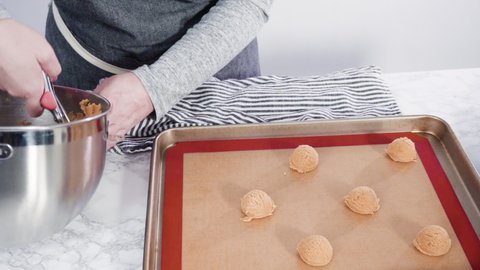Step by step. Scooping peanut butter cookies dough with dough scooper into the baking sheet.