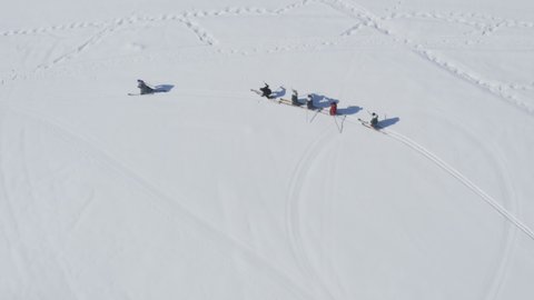 Tuva men in traditional clothing and fur skis walking in snow. Hemu Village, Xinjiang, China. Epic top down aerial view