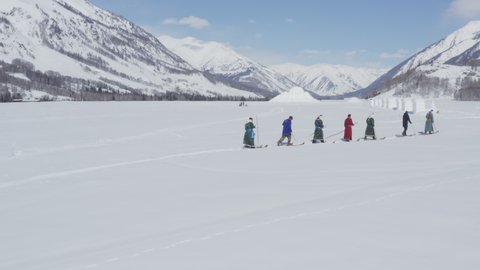 Tuva men history reenactment, hiking up snow mountain in ancient fur skis. Hemu Village, Xinjiang, China.