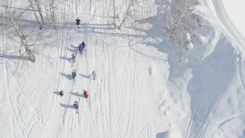 Aerial view of people walking uphill in skis on snow mountain