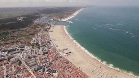 Long white sand beach and resort town of Nazare, Portugal. Establisher shot 
