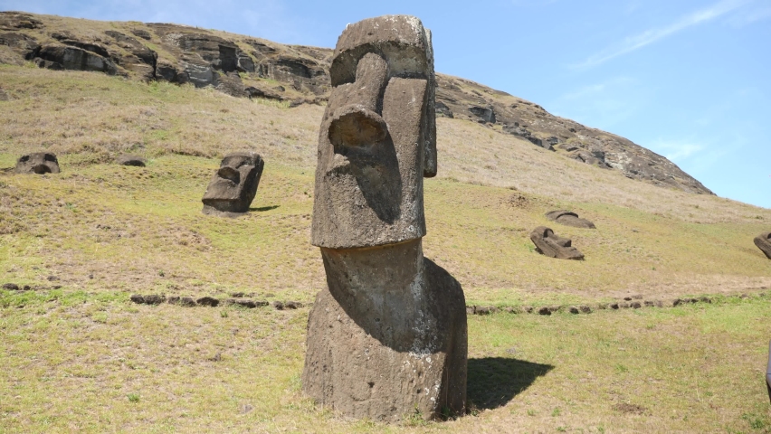 Mysterious Moais, ancient statues made of black volcanic rocks under the inactive volcano on Easter Island. Picturesque view of exotic island landscape and Giant megalith Moai statues. 4K Rano Raraku.