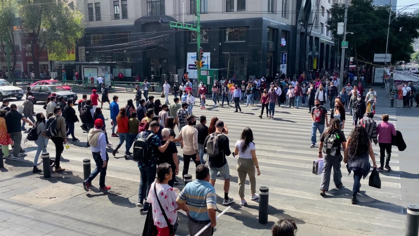 Mexico City, Mexico - November 7, 2021: People, wearing face masks to protect from COVID-19 pandemic, cross the street of a shopping commercial area of downtown CDMX.