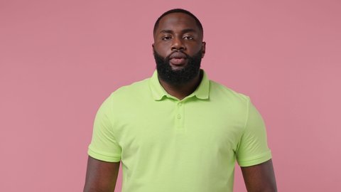 Joyful jubilant surprised young bearded african american man 20s wears green t-shirt say wow omg what spreading hands put arms on face isolated on plain pastel light pink background studio portrait