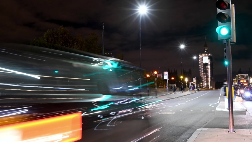 LONDON - NOVEMBER 3, 2021: MOTION TIMELAPSE PANNING shot of pedestrian crossing traffic lights on Westminster Bridge, London at night
