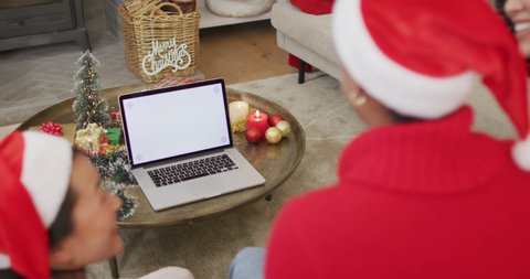 Happy diverse female friends in santa hats making christmas laptop video call, copy space on screen. christmas, festivity and communication technology.