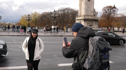 PARIS, FRANCE - OCT 30, 2021: People tourists taking pictures via smartphones on Paris landscapes sightseeings walking in wet autumn day