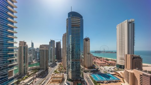 Panoramic view of the Dubai Marina and JBR area and the famous Ferris Wheel aerial timelapse untill sunset with shadows moving fast. Golden sand beaches in the Persian Gulf