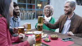 Young group of multiethnic friends having a drink at brewery pub after work - Happy young people celebrating together while toasting beer and socializing - Happy lifestyle concept