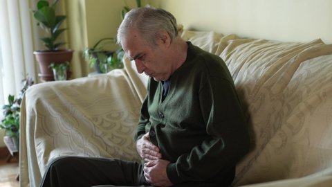 Elderly men feel stomach pain rubbing his belly and not feeling well.