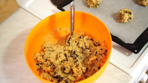 American chocolate chip cookies on a baking sheet on the stove next to a bowl of dough