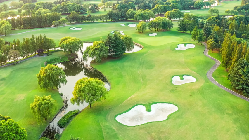 Aerial view of a green golf course.Green grass and trees with white sand trap.The drone flies over the golf course. Royalty-Free Stock Footage #1082074400
