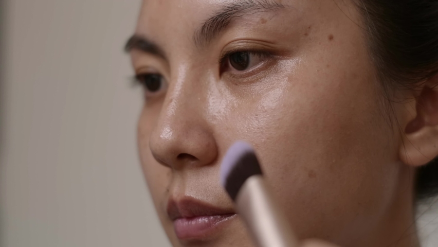 Closeup face, Asian woman using brush applying foundation on her face. Royalty-Free Stock Footage #1082080523