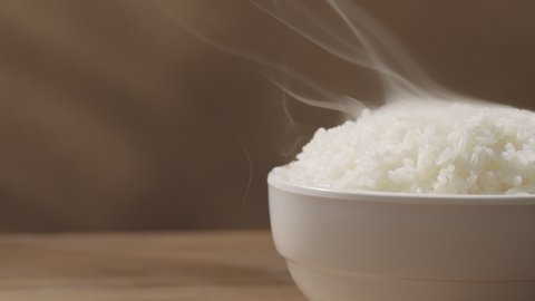 steaming rice in a bowl on the left side of the wooden table