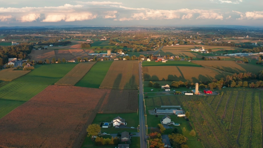 Beautiful aerial of rural farmland in USA at summer sunset. Golden hour shadows. Establishing shot.