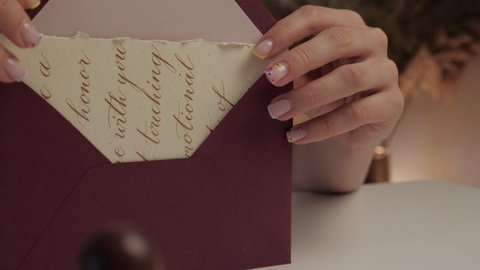 
woman puts a greeting card in envelope. calligraphy lettering and sealing wax