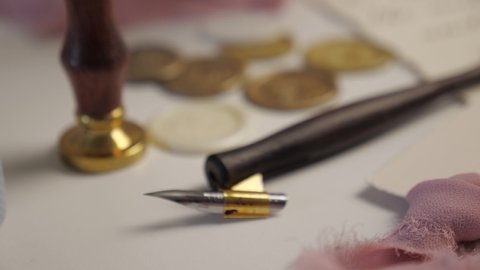 seal and stamps for sealing wax, nib pen for calligraphy. female hand raises a wooden writing pen