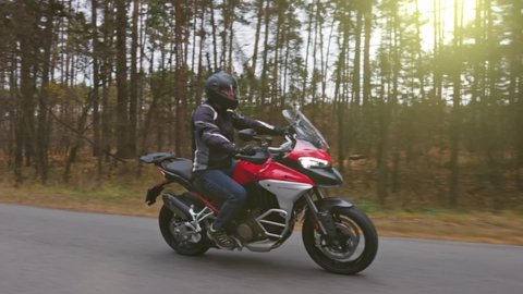 Biker man rides on the road on touring motorcycle. Handsome man driving stylish red motorbike. Travel on two wheels concept. Slow motion shot