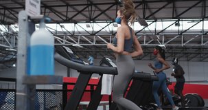 Animation of blue spiral rotating over women in face masks exercising on running machines. sport, fitness and technology during covid pandemic, digitally generated video.