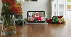 African american man wearing santa costume with face mask on christmas video call on laptop. christmas, festivity and communication technology during covid 19 pandemic.