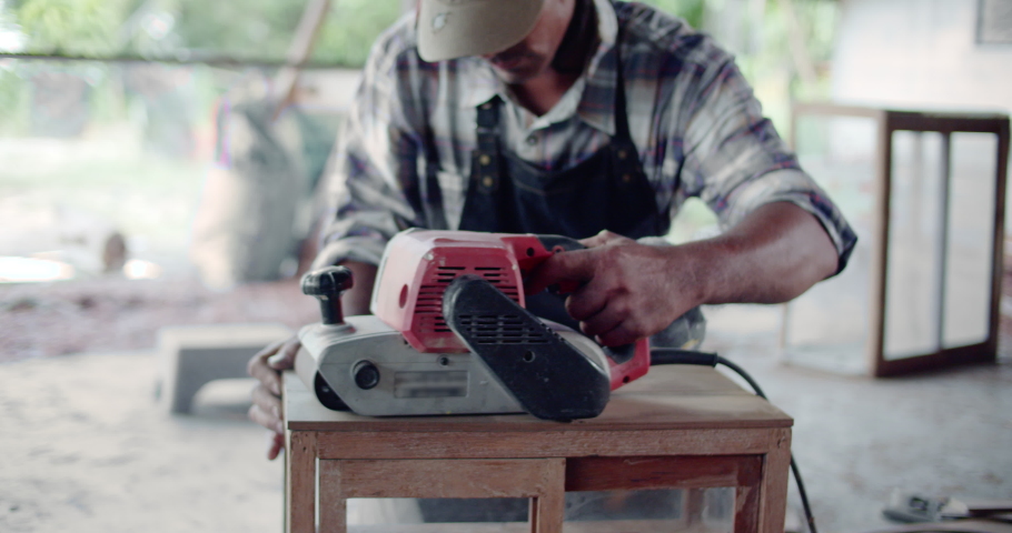 Slow motion scene of an Asian carpenter in a rural area is hired to repair woodworks and furnitures.