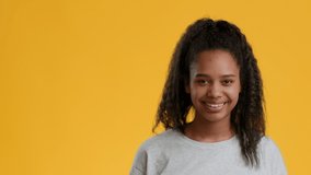 Cool Party. Funny Black Teenager Girl Gesturing Rock Sign And Sticking Out Tongue Over Yellow Background, Smiling To Camera. Female Youngster Having Fun Posing In Studio. Copy Space