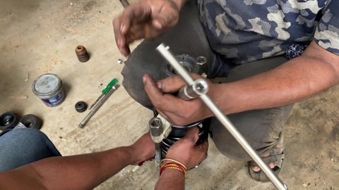 Auto mechanic assemble a car shock absorbers at garage station.