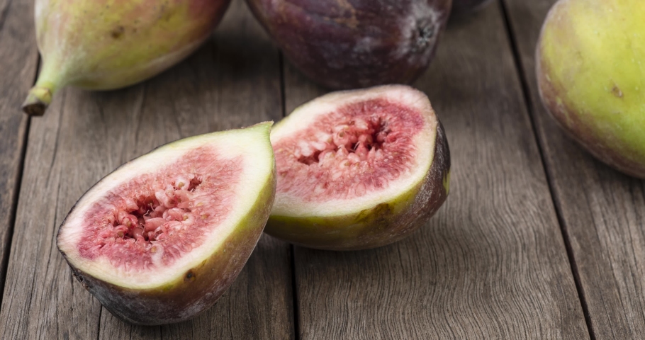 A group of figs over wooden table with cut fruit. | Shutterstock HD Video #1082100695