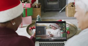 Two diverse senior female friends using laptop for christmas video call with boy on screen. christmas, festivity and communication technology.