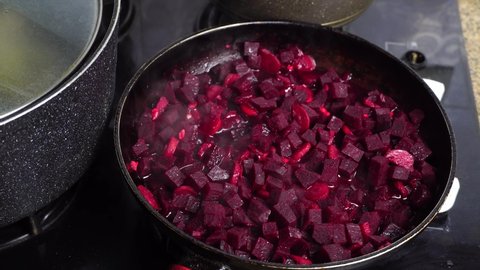 Cooking beetroot in a frying pan. Roasting for cooking borscht. Ukrainian cuisine. Mixing of crushed beets on a gas stove. Preparation of salad or soup.