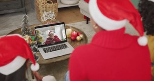 African american family with santa hats using laptop for christmas video call with woman on screen. christmas, festivity and communication technology.