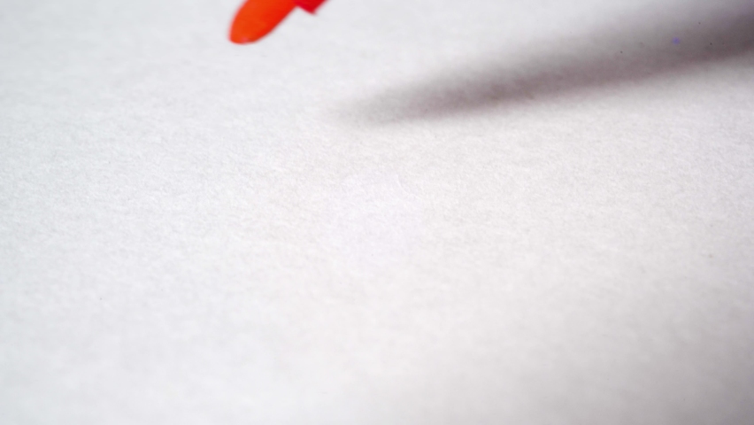 Close-up red marker drawing a smiling face on white paper