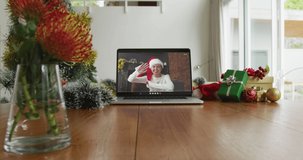 Smiling caucasian woman wearing santa hat on christmas video call on laptop. christmas, festivity and communication technology.