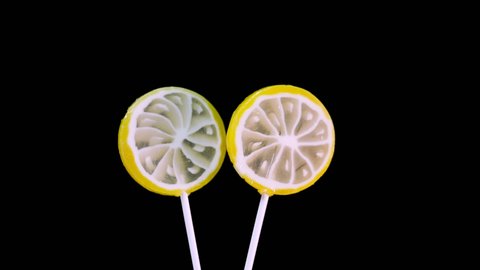 Lollipop spinning on a black background, baby lemon candy. Caramel sweets.