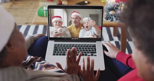 African american mother and daughter using laptop for christmas video call with family on screen. christmas, festivity and communication technology.