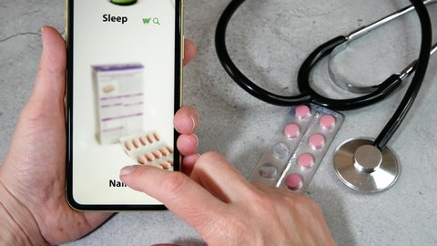 hand takes phone and search medications on pills and drugs background, online pharmacy concept