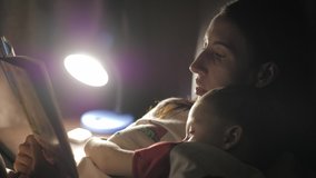 Child reading book in bed. Mother reading a bedtime story to her little son in bedroom. Education for children. Family before going to bed mother reads to her son book near a lamp in the evening. - Powered by Shutterstock - Get 15% off with code: PIKWIZARD15
