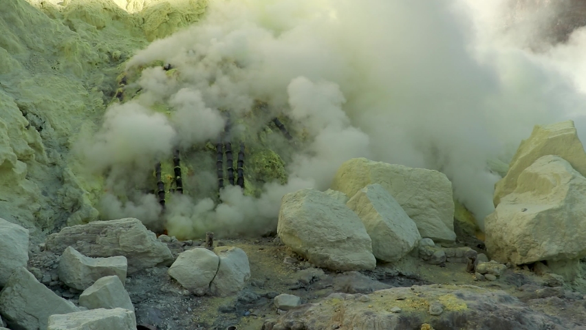 Cinematic aerial view of sulfur mine spewing toxic sulfur gas clouds at the crater of Kawah Ijen volcano, East Java, Indonesia Royalty-Free Stock Footage #1082155601