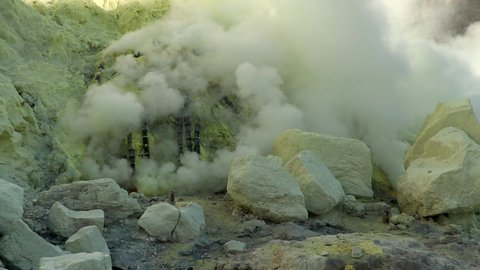 Cinematic aerial view of sulfur mine spewing toxic sulfur gas clouds at the crater of Kawah Ijen volcano, East Java, Indonesia