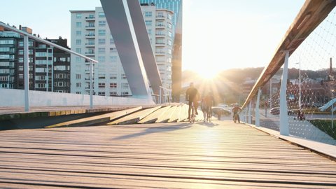 Liège, Belgium - November 10, 2021: Family time on a bike over wooden bridge designed by the Architect Calatrava at sunset. Scroll over River Meuse.