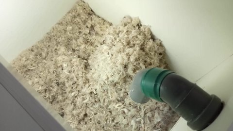 Chicken feathers and pillow fluff lie on the floor in the pillow dusting machine before starting the dust and debris cleaning procedure. Healthy sleep