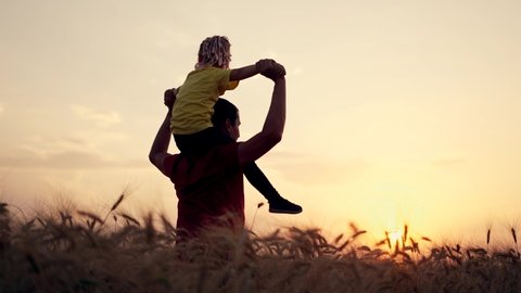 Happy family of farmer. Daughter sits on farmer father neck .Family at sunset in wheat field. Businessman in wheat field with his daughter. Businessman father holding daughter around his neck