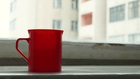 a red mug stands on the windowsill by the window. 4k footage - Powered by Shutterstock - Get 15% off with code: PIKWIZARD15