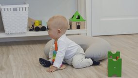 Baby sitting on the floor playing with toys, cute little baby boy having fun exploring new world around him at home. High quality 4k footage