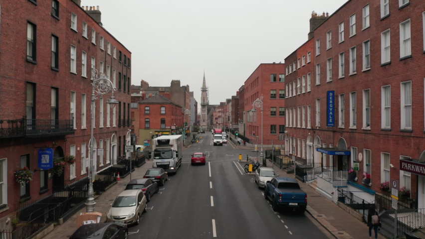 Cars driving through streets and crossroads. Forwards fly between red brick houses on sides. Dublin, Ireland